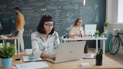 A professional reflecting while working on a laptop
