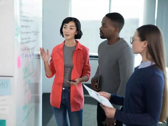 A leader sharing ideas with colleagues at a whiteboard