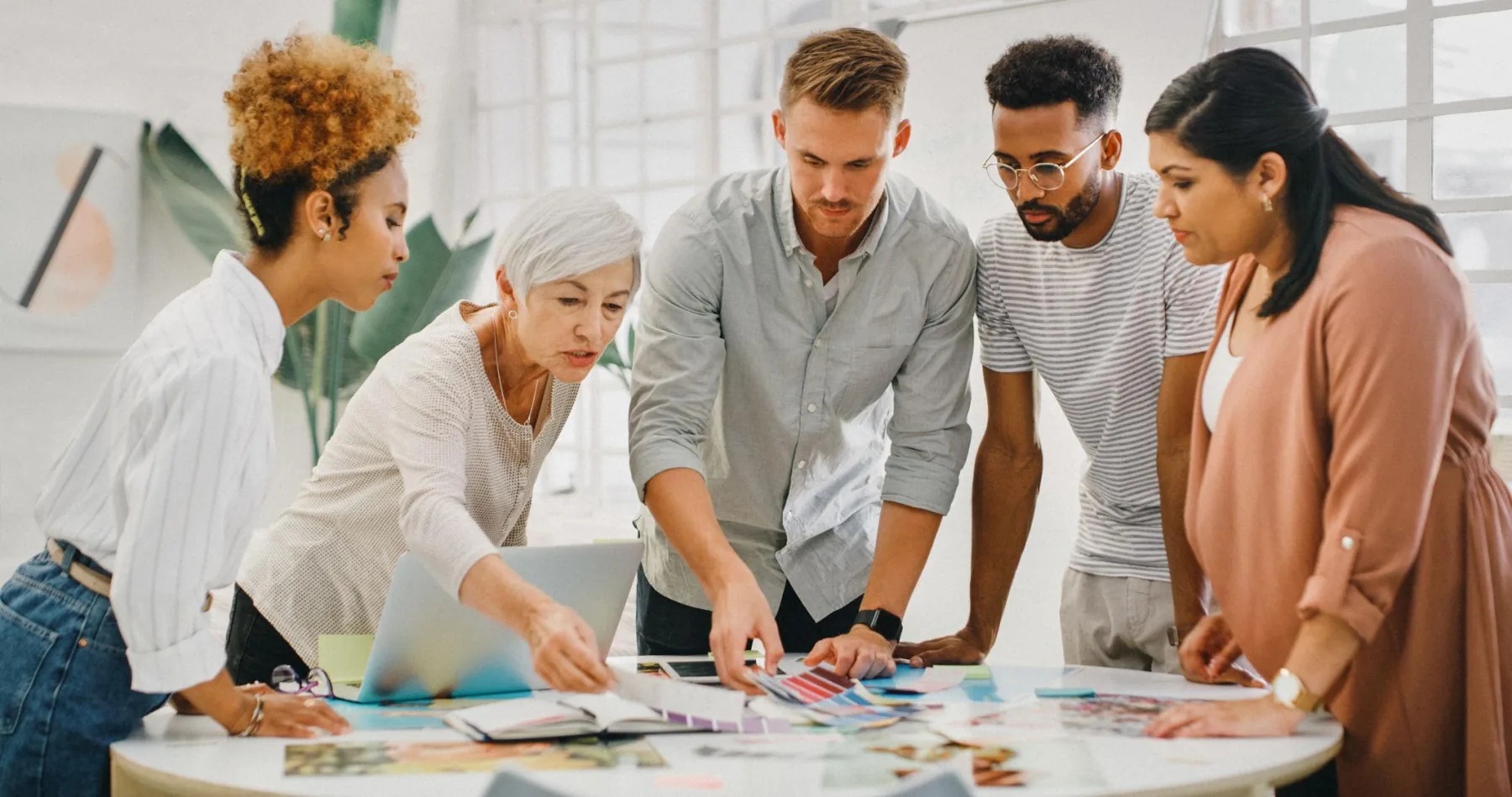 A team leaning in together over plans on a round table